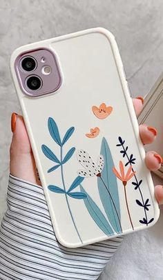 two women holding up their phone cases with hearts and flowers painted on the back of them