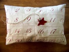 a white pillow with red numbers on it and a star hanging from the front, sitting on a wooden floor