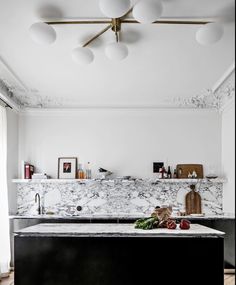 a kitchen with marble counter tops and white walls, along with fruit on the counter