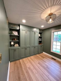 an empty room with green cabinets and wood floors