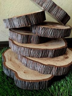 a stack of wood slices sitting on top of green grass next to a white wall