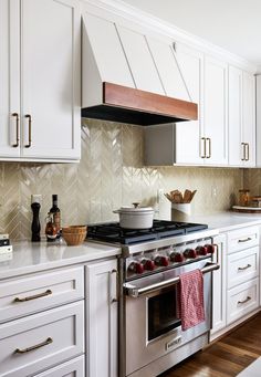 a stove top oven sitting inside of a kitchen next to white cabinets and wooden floors