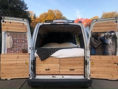 the back end of a white van with two beds in it