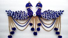 a blue and white peacock broochle with beads on it's back end