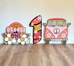 three wooden signs with flowers and the number one, two vw busses in front of them