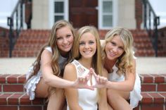 three beautiful young women sitting next to each other in front of a brick wall and stairs