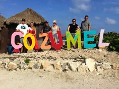 four people standing in front of a sign that says cozumel