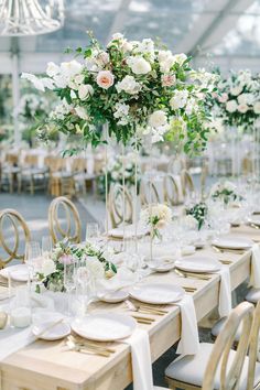 a long table with white and green flowers in tall clear vases on each side