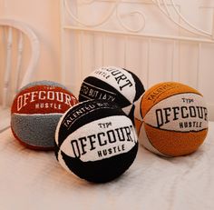 three different types of basketballs sitting on a white bed with an iron headboard in the background