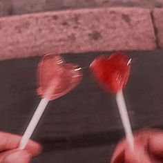 two heart shaped lollipops being held by someone