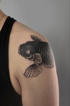 a woman's shoulder with a fish tattoo on it