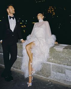 a man in a tuxedo standing next to a woman wearing a white dress