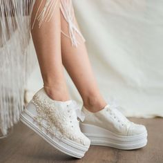 a woman's legs with white shoes and fringes on the bottom of them