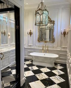 a bathroom with black and white checkered flooring, chandelier above the bathtub