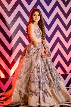 a woman in a long dress posing for a photo on a stage with an abstract background