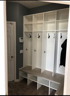 a room with some white shelves and coat racks