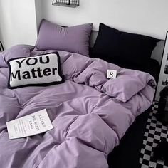 a bed with purple comforter and pillows in a room next to a black and white checkered floor