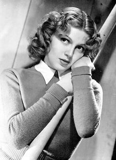 an old black and white photo of a woman leaning against a wall with her hand on her head