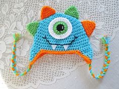 a crocheted hat with an eyeball on the front and side, made to look like a monster's head