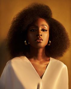 a woman with an afro is posing for a photo in front of a yellow background