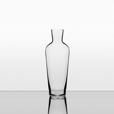 a clear glass vase sitting on top of a reflective surface with reflection in the water