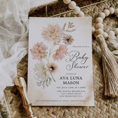 a baby shower with flowers and tassels next to it on a wicker mat