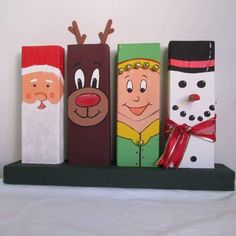 four wooden christmas decorations on a shelf with santa claus, snowman and reindeer faces