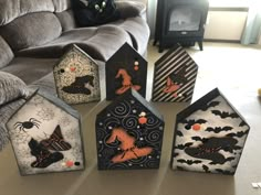 five halloween houses are sitting on the table in front of a couch and black cat