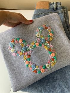 someone is holding up a handmade bag with flowers on it and an o symbol