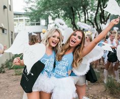 two girls dressed in white and blue posing for the camera with angel wings on their shoulders