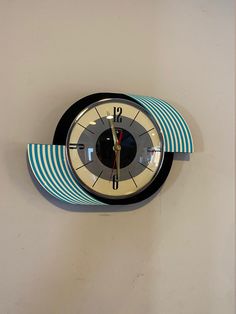 a clock that is on the wall with blue and white stripes around it's face