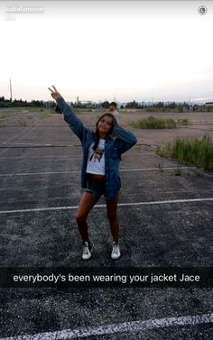 a woman is standing in an empty parking lot with her arms up and hands out