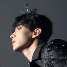 a close up of a person wearing a black jacket and water droplets on his hair