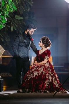 a man standing next to a woman in a red dress on top of a stage