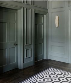 an empty room with green walls and wood flooring on the other side is a black and white checkered rug