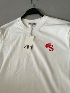 a white t - shirt with red lips on it and a tag hanging from the front