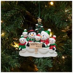 a christmas ornament hanging from a tree with snowmen and trees in the background