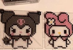 two cross stitch hello kitty coasters sitting on top of a table next to each other