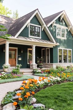 a green house with lots of flowers in the front yard