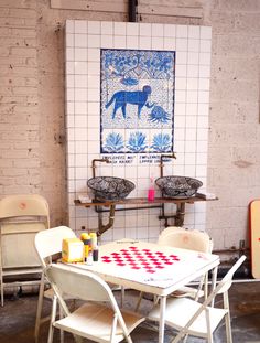 a table and chairs in a room with white tiles on the wall, two blue donkeys above them