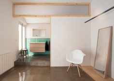 a white chair sitting on top of a hard wood floor next to a mirror and radiator