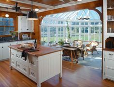 an open kitchen with white cabinets and wood flooring on the walls, along with a breakfast nook