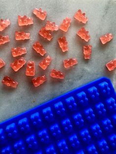 some red and blue gummy bears are next to a plastic tray with holes in it