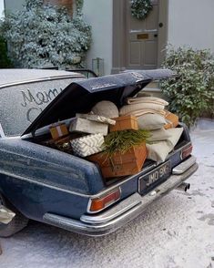 an old blue car is loaded with presents and wrapped in wrapping on the snow covered driveway