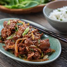 a plate full of food with chopsticks next to it on a wooden table