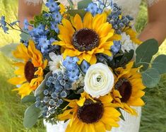 a bride holding a bouquet of sunflowers and blue flowers