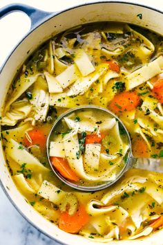 a pot filled with chicken noodle soup on top of a table