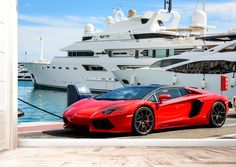 a red sports car is parked in front of a yacht