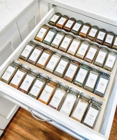 a drawer full of jars filled with different types of spices and seasonings on top of a wooden floor