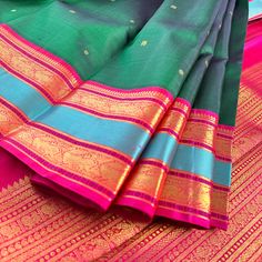 Introducing this magnificent handwoven korvai kanjivaram silk saree, adorned with buttis in rich emerald green body and deep pink contrast beautifully in the border and pallu, accentuated by a rama blue woven band and traditional gold zari motifs. Experience a perfect blend of traditional Indian artistry and modern elegance. Approximate Length 6.5 mtrs (inclusive of blouse length) Approximate Height - 48 - 52" Approximate weight - 1.7 lbs Saree comes with fall, picot and tassels done when applicable. Blouse piece is cut. Kindly Note : The colors you see on your device may vary due to the color reproduction, brightness and resolution of individual devices. If you'd like more clarity before your purchase, please contact our support team. Multicolor Paithani Silk Saree With Tilla, Multicolor Paithani Silk Saree With Tilla Details, Green Saree With Border In Traditional Drape, Green Art Silk Dupatta With Tilla Detail, Green Tilla Art Silk Dupatta, Green Traditional Wear With Border For Festivals, Green Banarasi Silk Dupatta With Tilla, Green Saree With Border, Green Saree With Tilla For Traditional Ceremonies